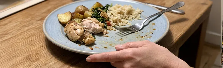 A barely-touched dinner plate being pushed away, fork resting on the edge